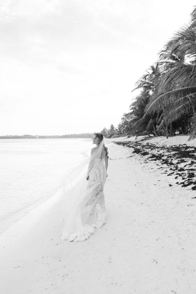 Black and white photo of bride walking along Los Cabos beach — destination wedding photographer in Mexico