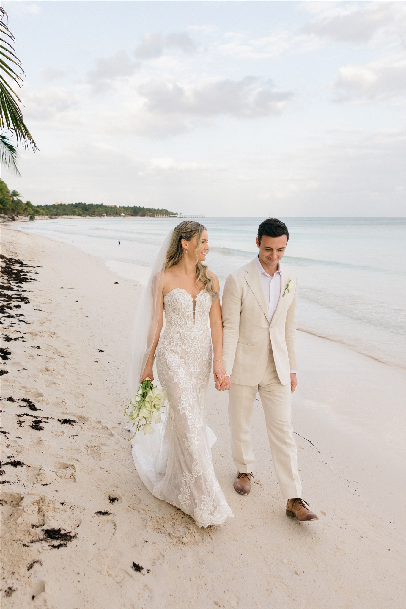 Couple walking together on white sand beach, Riviera Maya destination wedding